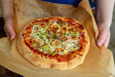 Aşçının elinde taze ev yapımı pizza. Üst görünüm