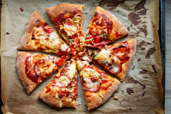 Pişirme kağıdında kesilmiş ev yapımı pizza dilimleri. Üst görünüm