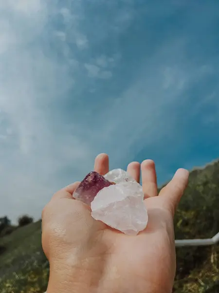 Kadının Eli Yükseldi ve Yumuşak Bulutlu Bir Turkuaz Gökyüzüne Karşı Kristalleri Tutuyor