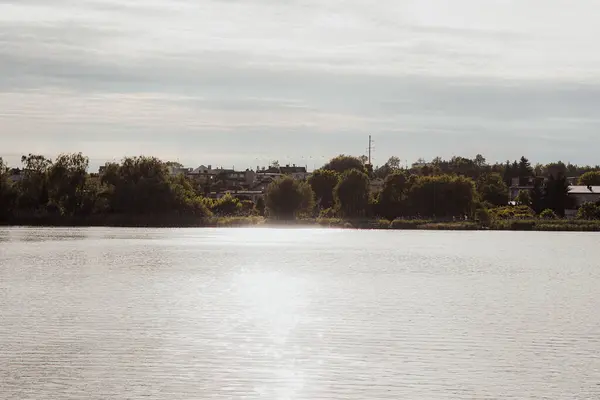 Arka planda Ormanı ve Güneş Işığı Suyu Yansıtan Huzurlu Göl