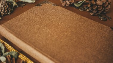 Vintage Hardcover Book with Metal Corners and Decorative Pinecones in a Cozy Scene