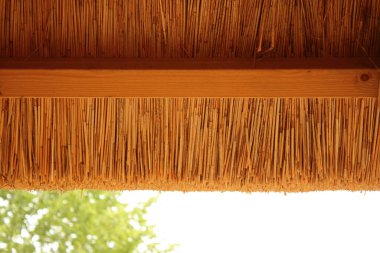 Gökyüzüne karşı ahşap kiriş çerçeveli Hasır Thatch Çatı 'nın Dış Kenarı