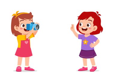 Küçük çocuk kamerayı tutuyor ve arkadaşının fotoğrafını çekiyor.