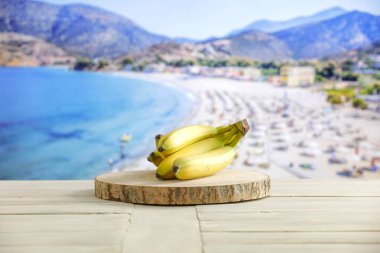 Tahta bir kasede taze meyve, beyaz tahta bir masanın üstünde, parlak deniz altyapısı bulanık.