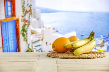 Tahta bir kasede taze meyve, beyaz tahta bir masanın üstünde, parlak deniz altyapısı bulanık.