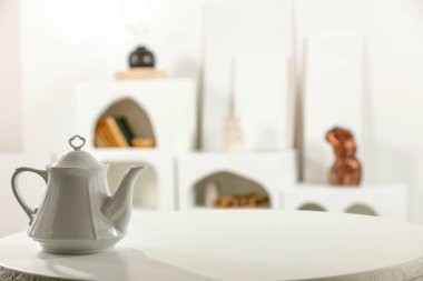 Farklı tabak takımları, fincanlar, fincan tabakları ve beyaz masa üstünde kahve demliği. İçi bulanık beyaz mutfak. Ürünler için alan.