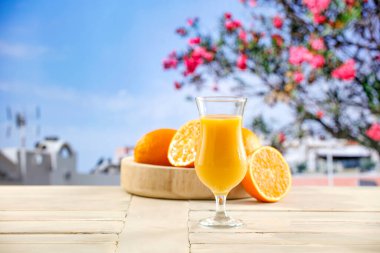 Güneşli bir günde, ahşap bir masada tropik bir meyvenin arka planında portakal suyu.