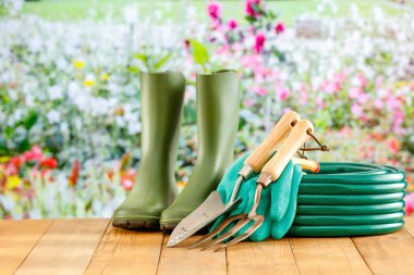 Bahar bahçesi aletleri ve çiçekler ahşap masada renkli arka planda..