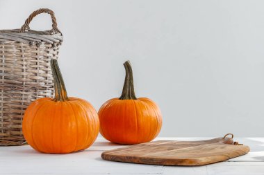 Hasır sepette bir balkabağı ve beyaz arka planda bir balkabağı. sonbahar konsepti.