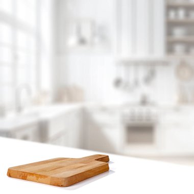 Beyaz masa zemininde ahşap kesim tahtasıyla bulanık beyaz mutfak önü ve parlak pencere doğal günlük ışık ve montaj ürünleri ekran alanı için kopyalama alanı.