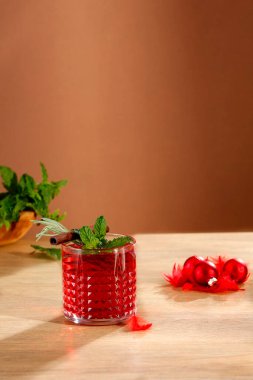 Taze biberiyeli kırmızı şarap içeceği ve ahşap masada ve kahverengi arka planda nane yaprakları.. 