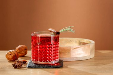 Kırmızı meyve taze biberiye ile sıcak şarap ve ahşap masa ve kahverengi arka plan üzerinde cam nane yaprakları. 