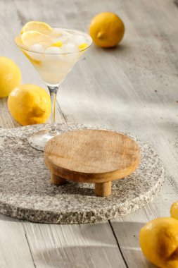 Limonlu ve buzlu martini bardağında su kokteyli. Mocktail ve limonlar ahşap masaya saçılmış. Ürünler için alanı kopyala.