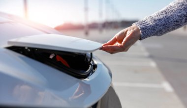 Elektrikli arabadaki akünün kapağını açmak için kesilmiş kadın eli.