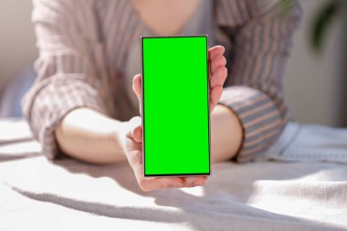 Bulanık arka planda elinde boş akıllı telefonu olan bir kadın..