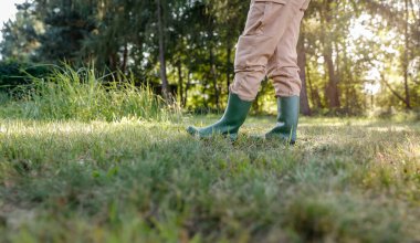 Bahçıvan bej pantolon ve yeşil lastik çizme giyiyordu. Ağaçlarla çevrili yemyeşil çimlerde..