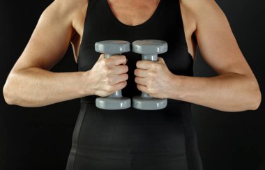 Kol ve halterli siyah aktif giyimli güçlü bir kadın vücudu. Vücut ağırlıklarla çalışıyor. Spor salonundaki atletik kadın.