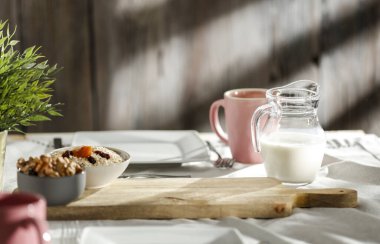 Waffle, kruvasan, süt ve ahşap masada sıcak kahveyle sıcak bir sabah kahvaltısı. Arka planda sıcak güneş ışığı.