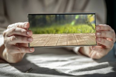 Telefon ekranında yazı ve ürün için fotokopi alanı olan, ahşap masa yaylı akıllı telefonu tutan kadınların yakın çekimi. Modern mobil ve model konsepti. 