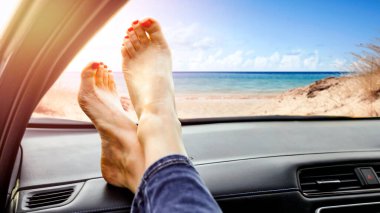 Bacaklar plajdaki gösterge panelinde dinleniyor. Yaz gezisi yaşam tarzı. Marka ya da metin yerleştirme için boş alan. Rahatlatıcı sürüş ve seyahat özgürlüğü kavramı.