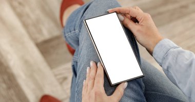 İnternette ve internet mağazalarında gezinen, akıllı telefonuyla alışveriş yapan sıcak bir evde rahatça oturan bir kadın. Metin, reklam, uygulama tasarımı veya tanıtım modeli için boş kopya alanı.