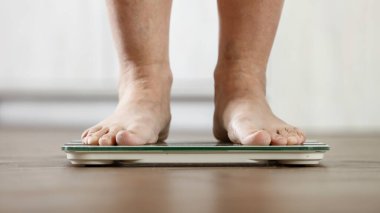 Ağırlık İzleme ve Sağlık Farkındalığı Konseptinde Duran Kadın Ayakları. Yaşlanma, Obezite ve Öz Bakım Teması.