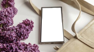 Bahar kompozisyonu içinde leylaklarla fotokopi alanı olan boş ekran cep telefonu. Düz konum ve beyaz arkaplan modeli.
