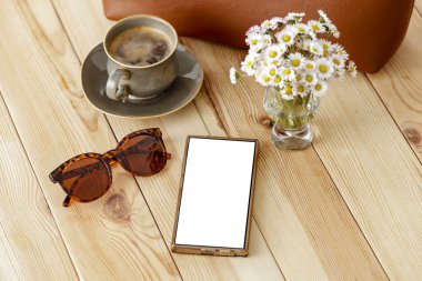  Hoş bir kompozisyon, papatya çiçekleri ve ahşap masa üzerine kadın çantası, rahat bir arka plan. Metin veya ürün için kopyalama alanı olan boş ekranlı akıllı telefon. Anneler Günü, Kadınlar Günü, doğum günü tebriği veya bahar tasarım projesi kartı.