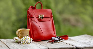 Bahar aksesuarları, kahve ve papatya çiçekleri ahşap masa üzerinde doğal gün ışığı ve bahçe düzeninde..