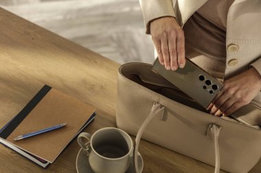 Masanın üstünde el çantası taşıyan bir kadının yakın plan fotoğrafı. İş günü için hazırlanmayı öneriyor. İşten Önce El Çantası Sabah Ofisi Hazırlık Sahnesi.