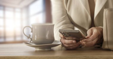 Evde Kahve ve Smartphone Sabah Dijital Programı ile Dinlenen Kadın. Ev Masasında Telefon Taranıyor