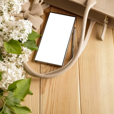 Metin veya ürün için kopyalama alanı olan ahşap bir masanın üzerinde düz bir akıllı telefon yatıyordu. Moda, kozmetik, yaşam tarzı proje tasarımları veya ürün yerleştirme temaları için mükemmel