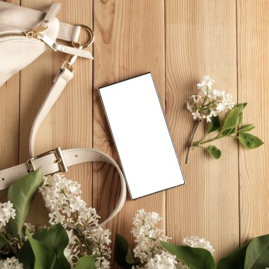 Metin veya ürün için kopyalama alanı olan ahşap bir masanın üzerinde düz bir akıllı telefon yatıyordu. Moda, kozmetik, yaşam tarzı proje tasarımları veya ürün yerleştirme temaları için mükemmel