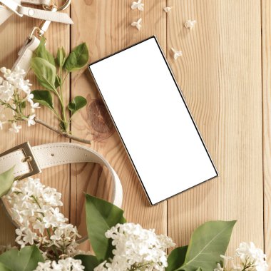Metin veya ürün için kopyalama alanı olan ahşap bir masanın üzerinde düz bir akıllı telefon yatıyordu. Moda, kozmetik, yaşam tarzı proje tasarımları veya ürün yerleştirme temaları için mükemmel
