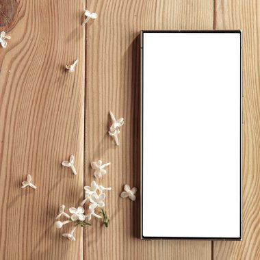 Metin veya ürün için kopyalama alanı olan ahşap bir masanın üzerinde düz bir akıllı telefon yatıyordu. Moda, kozmetik, yaşam tarzı proje tasarımları veya ürün yerleştirme temaları için mükemmel