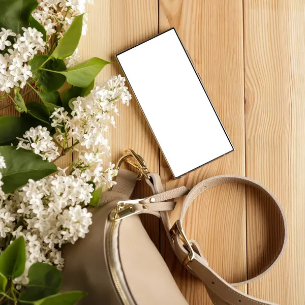 Metin veya ürün için kopyalama alanı olan ahşap bir masanın üzerinde düz bir akıllı telefon yatıyordu. Moda, kozmetik, yaşam tarzı proje tasarımları veya ürün yerleştirme temaları için mükemmel