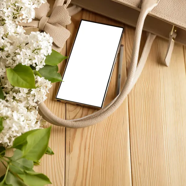 Metin veya ürün için kopyalama alanı olan ahşap bir masanın üzerinde düz bir akıllı telefon yatıyordu. Moda, kozmetik, yaşam tarzı proje tasarımları veya ürün yerleştirme temaları için mükemmel
