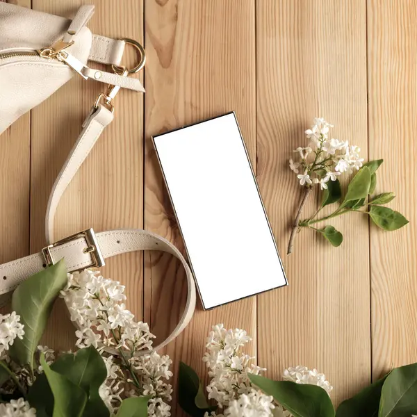 Metin veya ürün için kopyalama alanı olan ahşap bir masanın üzerinde düz bir akıllı telefon yatıyordu. Moda, kozmetik, yaşam tarzı proje tasarımları veya ürün yerleştirme temaları için mükemmel