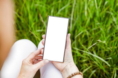 Doğal yeşil yeşillik bahçesi arka planı ve doğal gün ışığı için metin alanı olan boş ekranlı akıllı telefon.