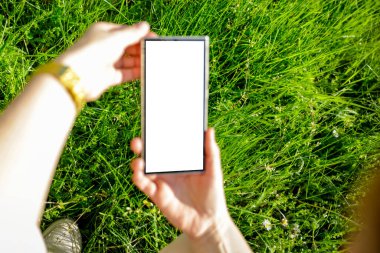 Açık ekran ve boş ekranlı akıllı telefon. Doğal yeşil bahçe arka planında güpegündüz çimen ve doğal yapraklarla yazı yazmak için yer var. Boşluğu kopyala.