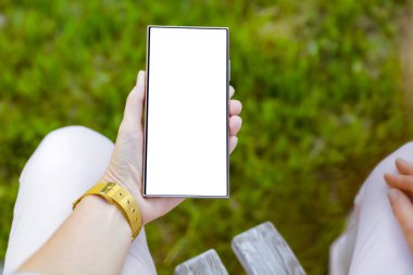 Açık ekran ve boş ekranlı akıllı telefon. Doğal yeşil bahçe arka planında güpegündüz çimen ve doğal yapraklarla yazı yazmak için yer var. Boşluğu kopyala.