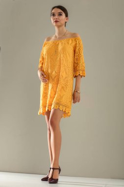 Açık gri duvarın önünde poz veren genç bir kadının stüdyo portresi. Tarafsız arka plan ve yumuşak ışıklandırma ve çok yönlü görünüm moda editörleri, model portföyleri, reklam modelleri veya minimalist güzellik ve yaşam tarzı kavramları için uygundur..