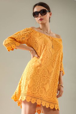 Açık gri duvarın önünde poz veren genç bir kadının stüdyo portresi. Tarafsız arka plan ve yumuşak ışıklandırma ve çok yönlü görünüm moda editörleri, model portföyleri, reklam modelleri veya minimalist güzellik ve yaşam tarzı kavramları için uygundur..