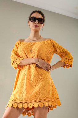 Açık gri duvarın önünde poz veren genç bir kadının stüdyo portresi. Tarafsız arka plan ve yumuşak ışıklandırma ve çok yönlü görünüm moda editörleri, model portföyleri, reklam modelleri veya minimalist güzellik ve yaşam tarzı kavramları için uygundur..