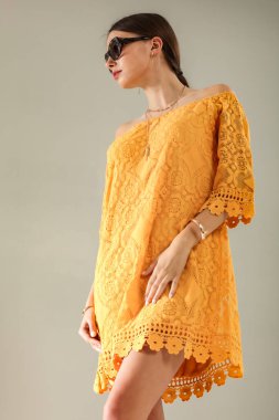 Açık gri duvarın önünde poz veren genç bir kadının stüdyo portresi. Tarafsız arka plan ve yumuşak ışıklandırma ve çok yönlü görünüm moda editörleri, model portföyleri, reklam modelleri veya minimalist güzellik ve yaşam tarzı kavramları için uygundur..