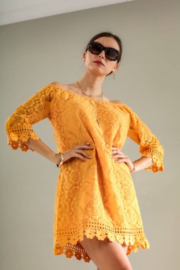 Açık gri duvarın önünde poz veren genç bir kadının stüdyo portresi. Tarafsız arka plan ve yumuşak ışıklandırma ve çok yönlü görünüm moda editörleri, model portföyleri, reklam modelleri veya minimalist güzellik ve yaşam tarzı kavramları için uygundur..