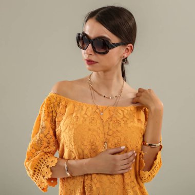 Açık gri duvarın önünde poz veren genç bir kadının stüdyo portresi. Tarafsız arka plan ve yumuşak ışıklandırma ve çok yönlü görünüm moda editörleri, model portföyleri, reklam modelleri veya minimalist güzellik ve yaşam tarzı kavramları için uygundur..