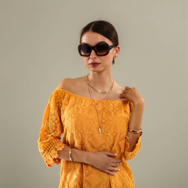 Açık gri duvarın önünde poz veren genç bir kadının stüdyo portresi. Tarafsız arka plan ve yumuşak ışıklandırma ve çok yönlü görünüm moda editörleri, model portföyleri, reklam modelleri veya minimalist güzellik ve yaşam tarzı kavramları için uygundur..