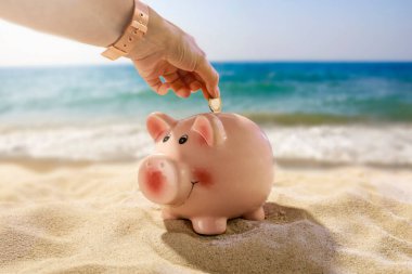 Elinde bozuk para olan bir kumbara. Bulanık plaj, deniz ve gökyüzü arka planı, ürün yerleştirme ve metin için alan. İş ve tatil konsepti için para biriktirme.
