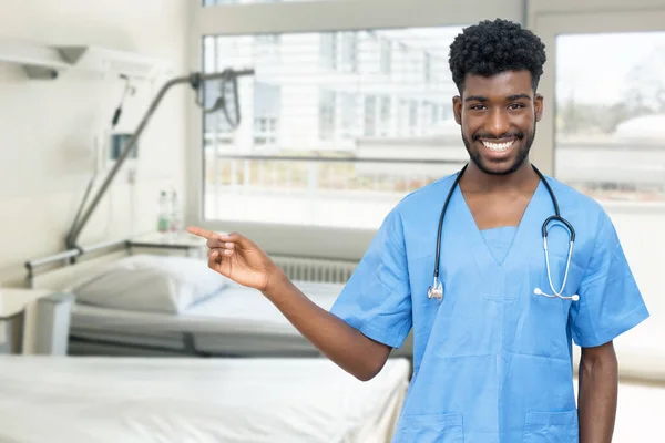 Νεαρός Αφροαμερικανός Γιατρός Νοσοκόμος Που Δείχνει Πλάγια Στο Δωμάτιο Του — Φωτογραφία Αρχείου